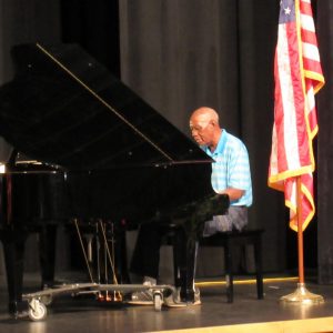 Mr. Luchus plays the piano on the stage at the Carolyn Harris Performing Arts Center